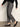 A person wearing Sanctuary Clothing’s 90s straight legging burnt olive plaid petites, a black long-sleeve sweater, and black patent leather flats stands against a plain light background. Their face is not visible.
