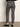A person is seen from behind wearing Sanctuary Clothing's 90s straight legging burnt olive plaid petites, featuring a high-waisted, slim-fit design in brown, blue, and gray hues, paired with black flats against a plain backdrop.