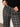 A person wearing a black sweater and pointing at the waistband of Sanctuary Clothing's 90s straight legging burnt olive plaid petites pants.