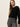 A woman with long straight blonde hair wears the Sanctuary Clothing 90s straight legging burnt olive plaid petites, paired with a black button-up sweater, standing against a plain off-white background.