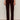 A person stands against a light background, wearing Sanctuary Clothing's velveteen brook bootcut pant in dark crimson petites, styled with black boots and a matching burgundy top; image is cropped from shoulders down.