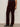 Only their lower body is visible as a person stands against a plain light background, wearing Sanctuary Clothing„¢s velveteen brook bootcut pant in dark crimson (extended sizing) and black heeled ankle boots.