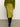 Only the lower half of a person wearing Sanctuary Clothing’s everyday midi skirt in martini olive is visible, paired with a green cardigan and black knee-high boots on a gray floor against a white wall.