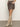 A person stands against a white wall, hands in pockets, wearing the Sanctuary Clothing camden skirt french kitty and light beige knee-high boots, with only their lower half visible.