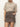A person wears the Sanctuary Clothing camden skirt french kitty, a high-waisted leopard print mini skirt, with a short-sleeve beige sweater and one hand in the pocket, standing against a plain white background.