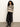 Woman wearing a patterned sweater and black skirt against a plain background