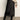 Person wearing a black satin skirt with lace hem and black boots against a plain background