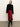 Woman wearing a black top and red skirt with black boots against a white background