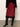 Red skirt with black lace trim worn with black knee-high boots on a neutral background