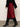 Person wearing a red skirt with black lace trim and black knee-high boots against a plain background