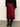 Person wearing a red satin skirt with black lace trim and black boots on a plain background