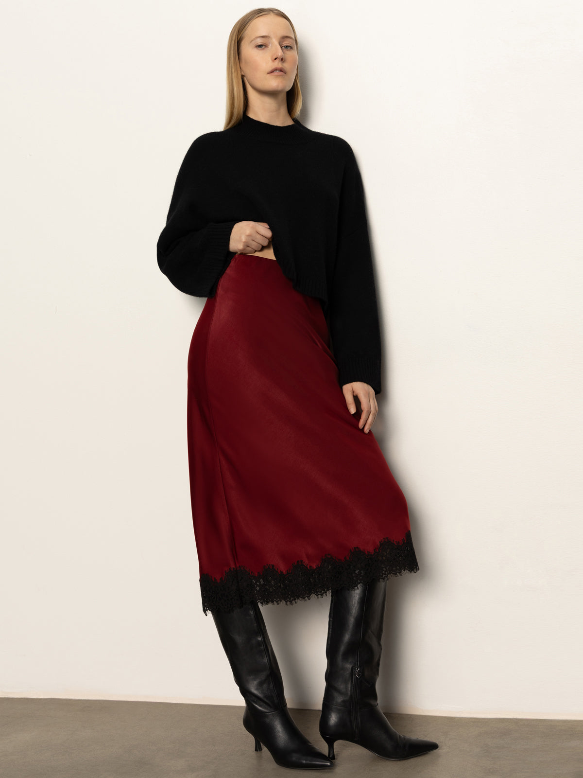 Woman wearing a black top and red skirt with black boots against a white background