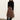 A woman stands against a plain wall wearing Sanctuary Clothing's nostalgia pleated midi skirt in mocha leo, paired with a black sweater and knee-high black boots. She looks down with her hands by her sides.