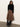 A woman stands against a plain wall wearing Sanctuary Clothing's nostalgia pleated midi skirt in mocha leo, paired with a black sweater and knee-high black boots. She looks down with her hands by her sides.
