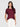 A woman with long dark hair models the Sanctuary Clothing perfect tee remix night berry, a maroon short-sleeve t-shirt, paired with white high-waisted pants against a plain light gray background, one hand in her pocket.