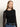 A person with long, straight blond hair wears the Sanctuary Clothing long sleeveperfect mesh tee in black, styled with blue jeans and a black belt, standing against a neutral background.