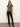 A woman with long brown hair and a neutral expression wears the Sanctuary Clothing double knit perfect tee winter leopard, styled with dark high-waisted pants and black ankle boots, standing against a plain light-colored wall.