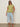 A woman in Sanctuary Clothing's knotted muscle tee bamboo (extended sizing), sunglasses, light blue cropped jeans, and beige sandals stands against a plain light wall on a gray floor.