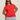 A woman wears the Sanctuary Clothing knotted muscle tee in cayenne (extended sizing) with light blue jeans. She stands against a light wall, has long brown hair, sunglasses, and her hands are behind her back.