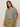 A woman with long brown hair models the Sanctuary Clothing notch neck tee light oat black stripe 3, paired with olive green drawstring pants, standing with one hand in her pocket against a plain light background.