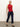 A woman with blonde hair tied back wears the Sanctuary Clothing sleeveless zip mock top in red energy black stripe, paired with dark blue cropped jeans and black flats, standing against a plain background and looking to the side neutrally.
