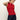 A woman wearing the Sanctuary Clothing sleeveless zip mock top in red energy with black stripes and dark blue jeans stands against a plain light background, looking down with one hand touching her neck.