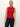 A woman stands against a light background wearing Sanctuary Clothing's sleeveless zip mock top in red energy with black stripes and dark blue jeans. She has her blonde hair tied back and gazes slightly to the side with a neutral expression.