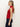 A woman in profile wears the Sanctuary Clothing sleeveless zip mock top in red energy black stripe and dark blue jeans. Her long blonde hair is tied in a low ponytail, and she stands against a plain background.