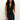 A woman with long curly hair models the Sanctuary Clothing sleeveless zip mock top in black, paired with dark blue jeans. She stands against a plain light background with one hand in her pocket.