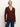 A woman stands against a plain light background, wearing the Sanctuary Clothing long sleeve textured top in chicory and blue jeans. She looks relaxed, with her left hand by her side and her right hand slightly forward.