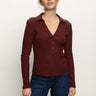 A woman stands against a plain light background, wearing the Sanctuary Clothing long sleeve textured top in chicory and blue jeans. She looks relaxed, with her left hand by her side and her right hand slightly forward.