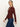 A woman with long blonde hair in a low ponytail wears the Sanctuary Clothing long sleeve textured top chicory with dark blue jeans, walking and looking at the camera against a plain light background.