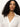 A woman with long, curly dark hair wears the Sanctuary Clothing long sleeve textured top in chalk, styled with an open collar and posing confidently against a plain light background.