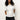 A woman with long curly hair wears the Sanctuary Clothing shirred waist dolman tee in white and dark jeans, standing against a plain light background with her hands behind her back.