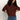 A person with long curly hair wears Sanctuary Clothing's boxy raglan tee in chicory and blue jeans, standing against a plain light background with hands on hips and head slightly tilted down.