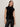 A woman with straight brown hair wears the Sanctuary Clothing funnel neck sequin top in black and black leather pants, standing against a plain light-colored background.