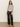 A woman with wavy brown hair and a neutral expression wears the Sanctuary Clothing fitted mesh button down top mother leo—a long-sleeved animal print blouse—against a plain background. She pairs it with black wide-leg leather pants and tan pointed-toe ankle boots.