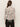 A woman with long brown hair is seen from the back wearing the Sanctuary Clothing fitted mesh button down top mother leo, a long-sleeve white blouse with black and brown animal print, paired with black leather pants.