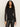 A woman with long curly hair wears the fitted mesh button down top in black by Sanctuary Clothing with black leather pants, standing against a plain light background and looking confidently at the camera.