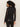 A woman with curly hair is seen from the back, wearing the Sanctuary Clothing fitted mesh button down top in black and black leather pants, standing against a plain light background.