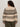 A person with curly hair is seen from the back wearing Sanctuary Clothing’s fairisle sweater light oat multi (extended sizing) with black geometric patterns and olive green pants.