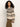 Woman with curly hair wearing Sanctuary Clothing's fairisle crew neck sweater in light oat multi and brown pants, standing against a plain light background and looking to the side.