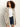 A woman with curly hair wears the Sanctuary Clothing openwork beach cardi in chalk black stripe over a white T-shirt and denim shorts, standing against a plain light background.