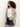 A woman with curly hair models the Sanctuary Clothing openwork beach cardi in chalk black stripe, styled over a white T-shirt and blue denim shorts, standing against a plain light background.