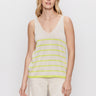 A woman with blonde hair wears Sanctuary Clothing's V Neck Knitwear Tank in Muslin Desert Lime Stripe and cream pants, standing against a plain white background.