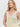 A woman with long blonde hair models the Sanctuary Clothing v neck knitwear tank in muslin desert lime stripe, a sleeveless beige top with light green horizontal stripes, against a plain white background.