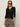 A woman wears the Sanctuary Clothing lightweight ribbed cardi in black, paired with leopard print pants, a black belt, red sunglasses, and gold hoop earrings against a plain light background.