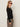 A woman with long, light brown hair wears red cat-eye sunglasses and the Sanctuary Clothing lightweight ribbed cardi in black, paired with leopard print pants. She stands sideways against a plain light background.