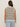 A person with long brown hair faces away, modeling the Sanctuary Clothing textured sweater vest macrame black stripe 4 with light blue jeans against an off-white background.