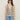 A woman wears the Sanctuary Clothing textured sweater vest macrame black stripe 3, paired with black sunglasses and light blue jeans, standing against a plain light background.